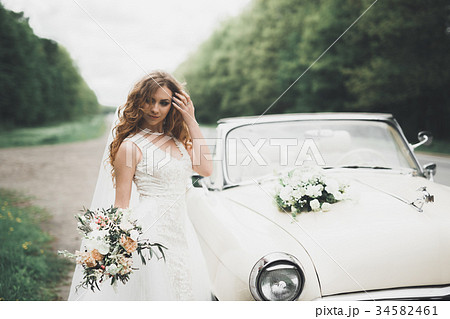 A beautiful bride posing near retro car outdoors A beautiful bride posing near retro car outdoors 34582461
