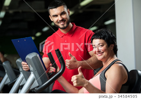 Smiling personal coach with female client in gym. 34584505