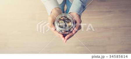Woman hands holding glass jar with coins inside Woman hands holding glass jar with coins inside 34585614