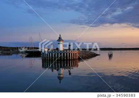 Small lighthouse and sailing boats at sunset. Small lighthouse and sailing boats at sunset. 34590383