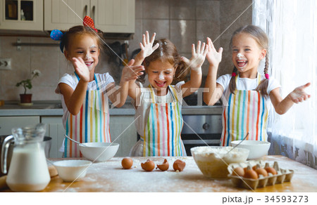 happy sisters children girls bake cookies, knead dough, play wit 34593273