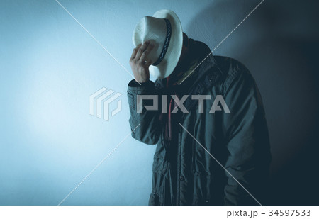 A man wearing hat against concrete wall surface A man wearing hat against concrete wall surface 34597533