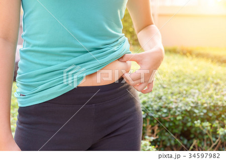 Chubby woman hand holding her own belly fat Chubby woman hand holding her own belly fat 34597982
