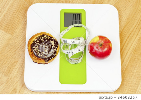 Chocolate bun and apple with measuring tape on ele Chocolate bun and apple with measuring tape on ele 34603257