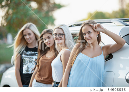 The young women standing near the car 34608058