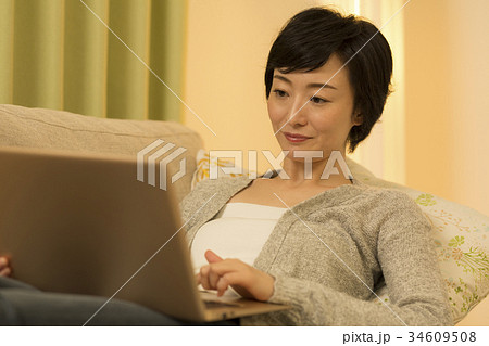 ソファでPCを打つミドル女性 34609508