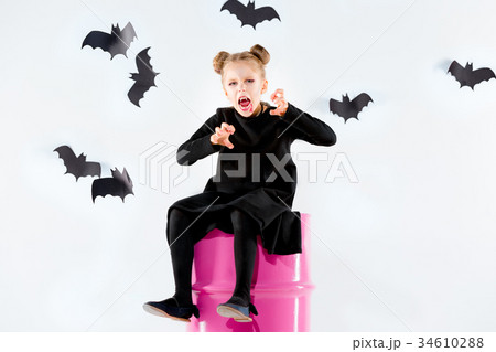 Little girl witch in black dress over magical 34610288