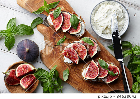 Fresh figs, basil and cream cheese bruschetta on white table 34628042
