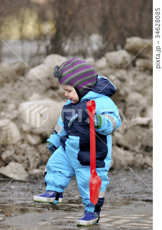Little boy stand with red shovel in pool Little boy stand with red shovel in pool 34628085