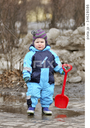 Little boy stand with red shovel in pool Little boy stand with red shovel in pool 34628086
