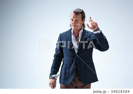 The mature barded man in a suit holding cane. 34628584