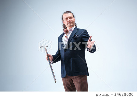 The mature barded man in a suit holding cane. 34628600