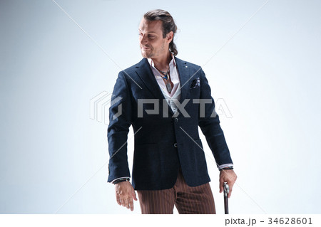 The mature barded man in a suit holding cane. 34628601