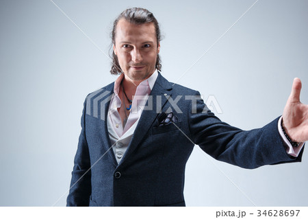 The mature barded man in a suit holding cane. 34628697