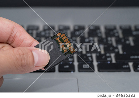hand holds SD card  with laptop background 34635232