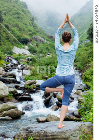 Woman in yoga asana Vrikshasana tree pose at 34654845