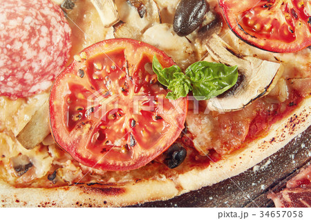 Closeup of pizza with salami, tomatoes and olives Closeup of pizza with salami, tomatoes and olives 34657058