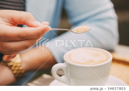Spoon in a female hand pouring sugar Spoon in a female hand pouring sugar 34657803