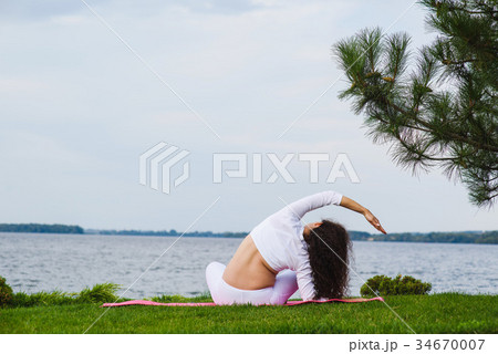 Pregnant woman is practicing yoga beside river Pregnant woman is practicing yoga beside river 34670007