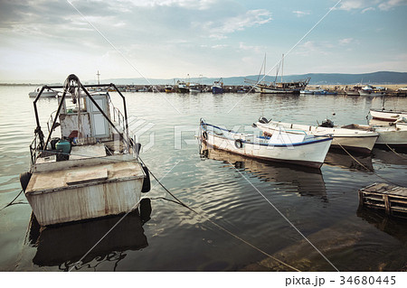 Small fishing boats are moored in port 34680445