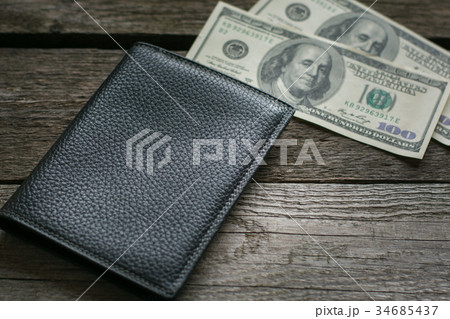 Black wallet and american dollar on wooden board. Black wallet and american dollar on wooden board. 34685437