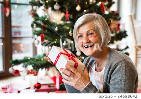 Senior woman in front of Christmas tree with 34688642