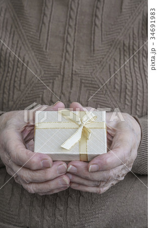 wrinkled hands holding gift 34691983