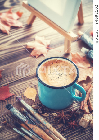 Coffee, brushes, paints, artistic canvas on easel. 34692102