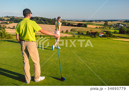 Man watching his partner striking the ball during 34693779