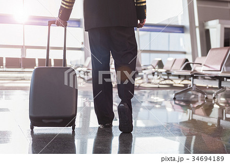 Male pilot going through terminal Male pilot going through terminal 34694189