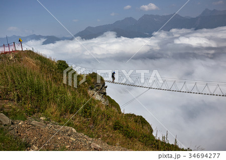 Man walking on suspension bridge and looking at Man walking on suspension bridge and looking at 34694277