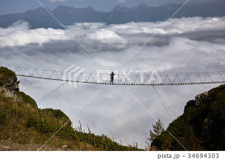Man walking on suspension bridge and looking at 34694303