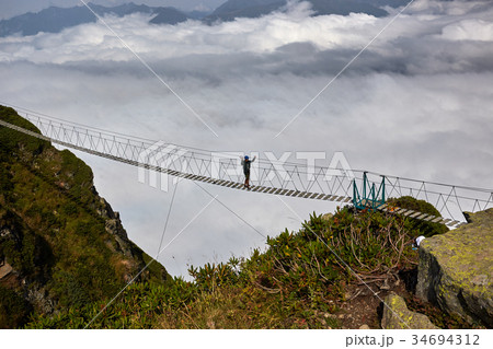 Man walking on suspension bridge and looking at Man walking on suspension bridge and looking at 34694312