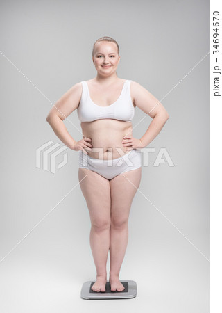 Happy fat girl measuring weight on balance Happy fat girl measuring weight on balance 34694670
