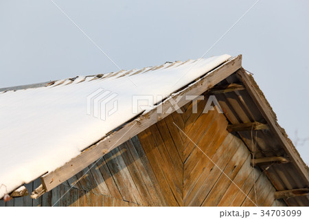 Snow on the roof of the house at sunset 34703099