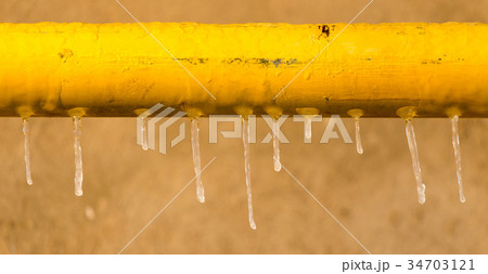 Icicles on a yellow pipe at sunset Icicles on a yellow pipe at sunset 34703121