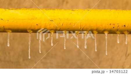 Icicles on a yellow pipe at sunset Icicles on a yellow pipe at sunset 34703122