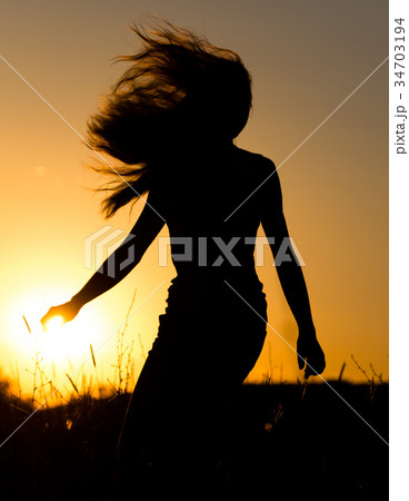 Silhouette of a girl with long hair at sunset 34703194