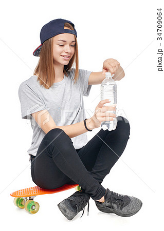 Teen girl in full length sitting on skate board 34709064