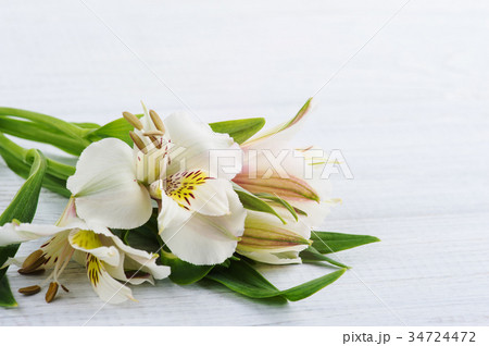Alstromeria flowers in the wooden box, lit candle Alstromeria flowers in the wooden box, lit candle 34724472