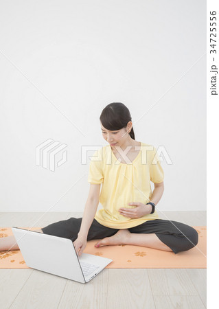 パソコンを見ながらマタニティーヨガをする女性 パソコンを見ながらマタニティーヨガをする女性 34725556