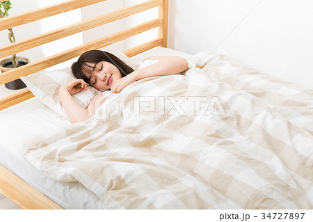 ベッドで眠る若い女性の写真素材