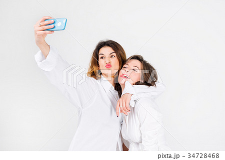 Two women posing taking selfie in light studio Two women posing taking selfie in light studio 34728468