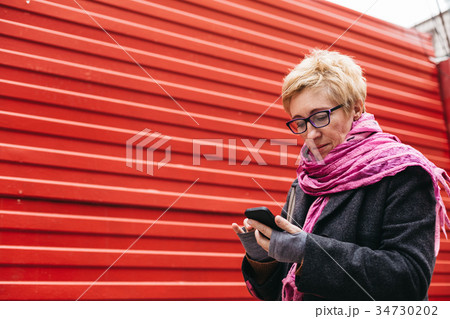 Woman texting at red wall Woman texting at red wall 34730202