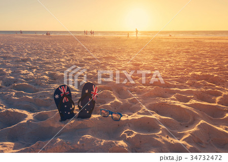 Thongs and sunglasses on beach sand Thongs and sunglasses on beach sand 34732472