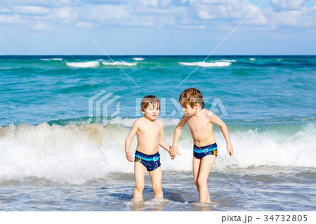 Two kid boys running on ocean beach in Florida 34732805