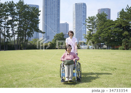 車いすで散歩する笑顔のシニアとヘルパーさん 車いすで散歩する笑顔のシニアとヘルパーさん 34733354