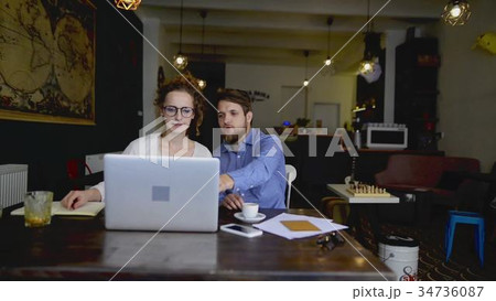 Two young designers with laptop working in cafe. 34736087