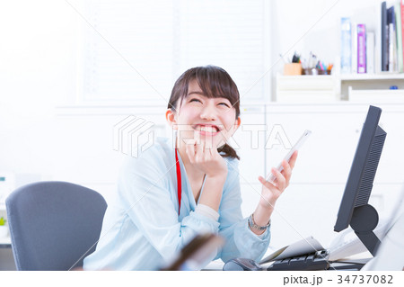 オフィスで嬉しそうに携帯電話を操作する女性社員 OL ビジネスマン サラリーマン オフィスイメージ オフィスで嬉しそうに携帯電話を操作する女性社員 OL ビジネスマン サラリーマン オフィスイメージ 34737082