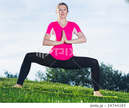 Adult woman in pink T-shirt is practising asanas 34744165